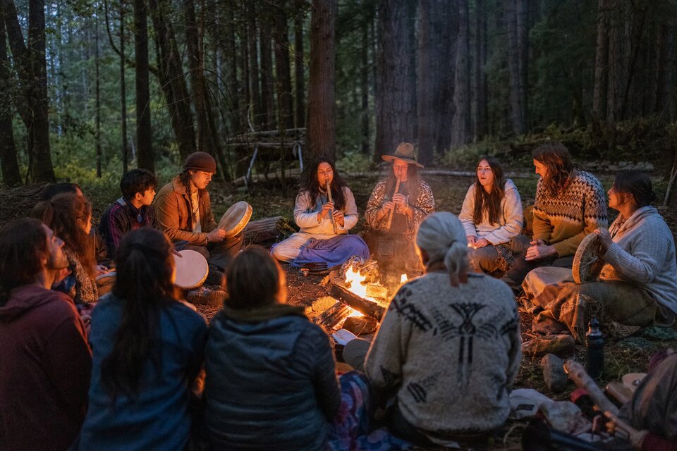 Village fire circle with people singing and connecting among the trees